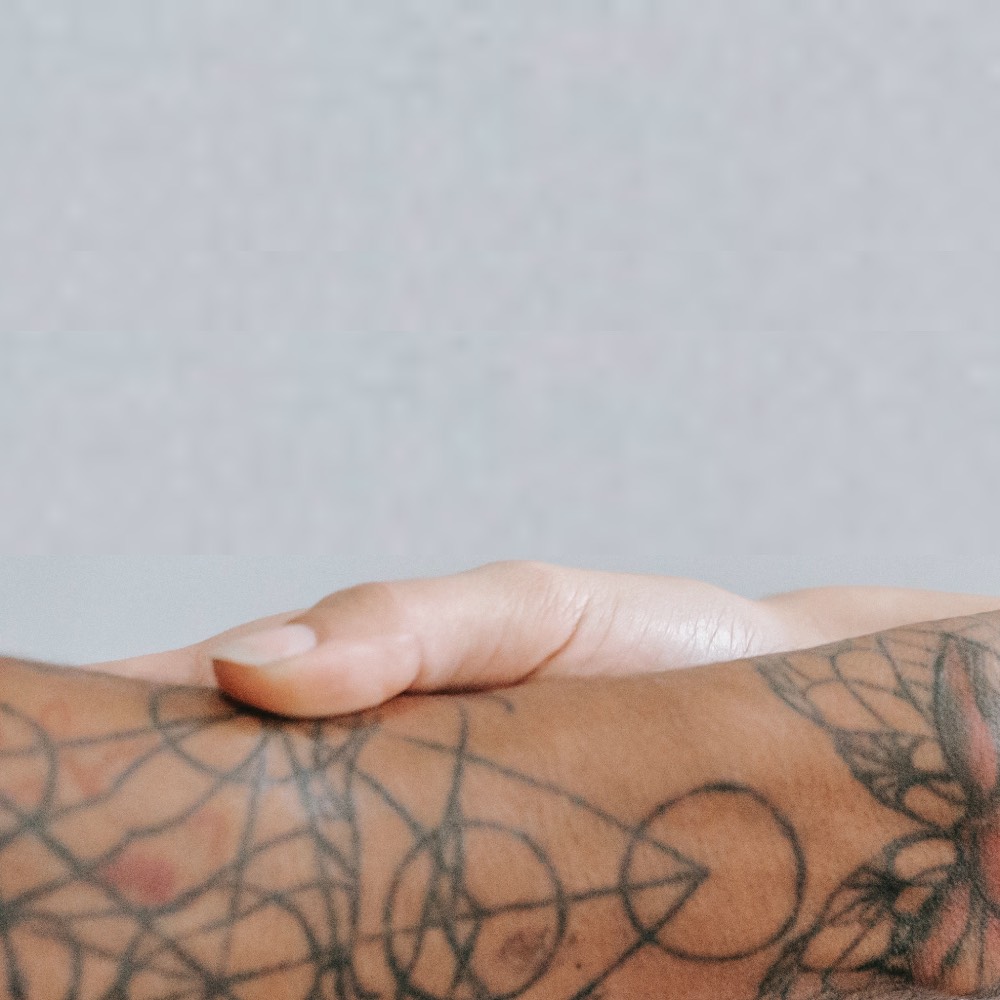 Hand touching body with tattoo